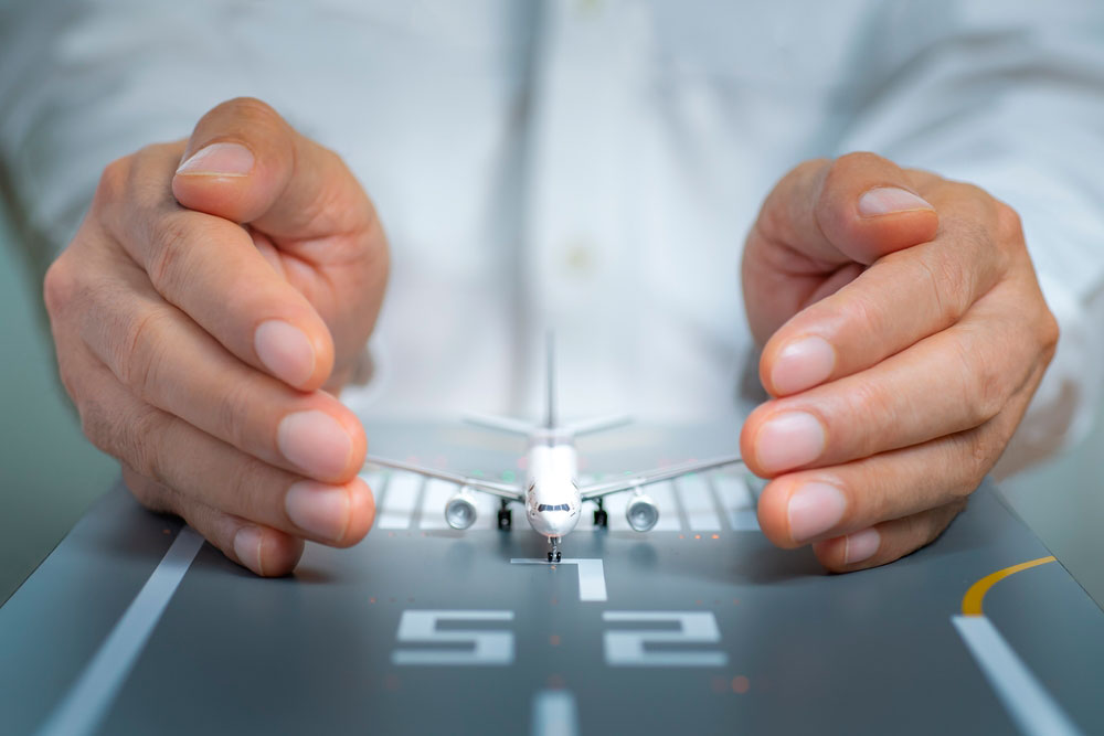 Manos protegen a maqueta de avión simbolizando la seguridad aérea